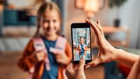 Saving memories in gadget. Selective focus on display of telephone recording video with first grade girl