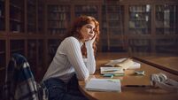 Bored redhead student thinking in library.