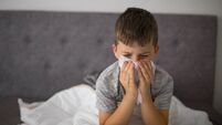 Sick little boy cleaning nose in bed