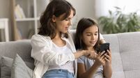 Engaged mom showing cute child girl how to use application