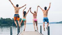 Group of friends jumping into the lake