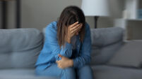 Stressed unhappy young woman sitting on sofa.