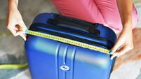 Young woman measuring travel luggage or suitcase before flight