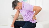 Man Having Backache While Sitting On Sofa
